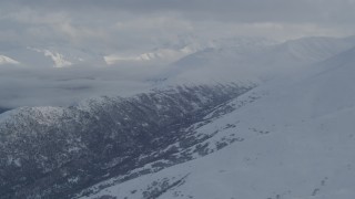 AK0001_1547 - 4K aerial stock footage the snowy Chugach Mountains, cloud covered Eklutna Lake Valley, Alaska
