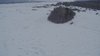 AK0001_1580 - 4K aerial stock footage flying over snow covered, frozen river and trees, Knik River Valley, Alaska