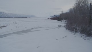 AK0001_1586 - 4K aerial stock footage flying over rivers in snow covered Knik River Valley, Alaska
