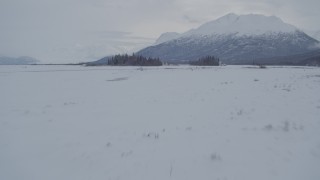 AK0001_1589 - 4K aerial stock footage fly over snowy ground toward Chugach Mountains, Knik River Valley, Alaska