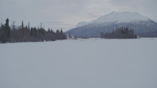 AK0001_1590 - 4K aerial stock footage flying low over snow covered, frozen ground and icy river, Knik River Valley, Alaska