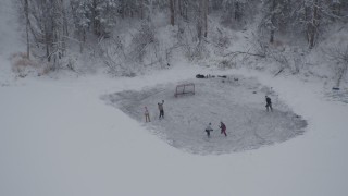 AK0001_1629 - 4K aerial stock footage kids playing ice hockey on iced over lake, Chugiak, Alaska in snow