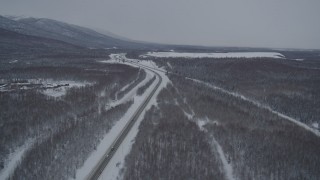 AK0001_1636 - 4K aerial stock footage snowy Glenn Highway stretching toward Chugach Mountains, Eagle River, Alaska