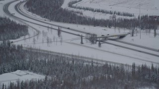 AK0001_1637 - 4K aerial stock footage flying by Eagle River Loop Road overpass over Glenn Highway, Alaska in snow
