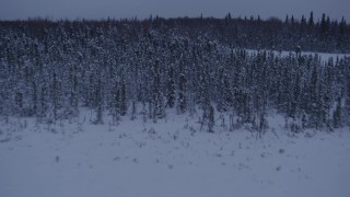 AK0001_1681 - 4K aerial stock footage flying over frozen, snowy ground and woods at twilight in Point MacKenzie, Alaska, reveal Downtown Anchorage