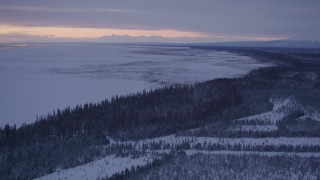 AK0001_1692 - 4K aerial stock footage following snowy, wooded shore of Point MacKenzie at twilight, Alaska
