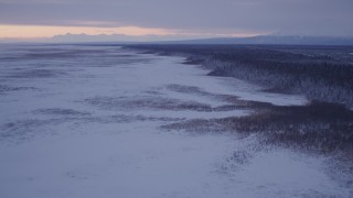 AK0001_1695 - 4K aerial stock footage flying over frozen, snow covered ground at twilight, Point MacKenzie, Alaska