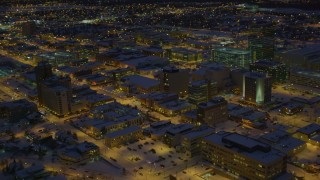 AK0001_1729 - 4K aerial stock footage orbit office buildings and streets in snow covered Downtown Anchorage at night, Alaska