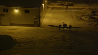 AK0001_1738 - 4K aerial stock footage an airplane rounding hanger at snowy Merrill Field, Anchorage, Alaska, night