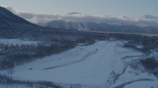 AK0001_1760 - 4K aerial stock footage descending toward snow covered Girdwood Airport, Alaska