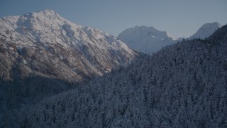 AK0001_1761 - Aerial stock footage of 4K aerial  video rounding snowy, wooded peak, reveal double peak, Chugach Mountains, Alaska