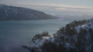 AK0001_1833 - 4K aerial stock footage rounding a snowy shore in the Harriman Fjord, Alaska