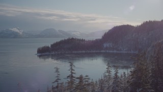 AK0001_1849 - 4K aerial stock footage flying toward the snowy, wooded shore of a bay, Port Wells, Alaska