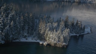 AK0001_1851 - 4K aerial stock footage descending toward water near snowy, wooded peninsula, Port Wells, Alaska