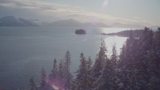 AK0001_1853 - 4K aerial stock footage ascend snowy, wooded shore reveal Chugach Mountains, Port Wells, Alaska