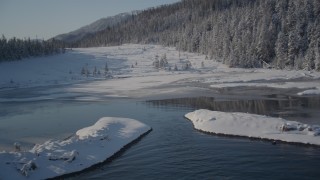 AK0001_1855 - 4K aerial stock footage fly over icy shore beside snowy forest in Port Wells, Alaska