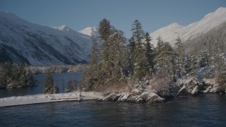 AK0001_1860 - 4K aerial stock footage orbiting by a snowy, wooded mountain and small islands in Port Wells, Alaska