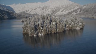 AK0001_1881 - 4K aerial stock footage rounding a snowy, wooded island in Hummer Bay, Port Wells, Alaska