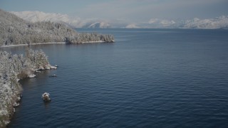 AK0001_1883 - 4K aerial stock footage flying by small islands toward snowy, wooded shore, Port Wells, Alaska