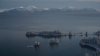 AK0001_1885 - 4K aerial stock footage fly over snowy, wooded shore, Chugach Mountains across Port Wells, Alaska