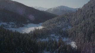AK0001_1898 - 4K aerial stock footage flying over snowy shore of Pigot Bay toward forested slopes, Alaska