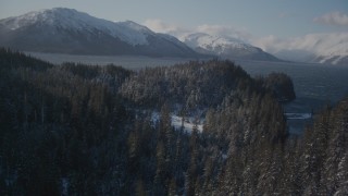 AK0001_1900 - 4K aerial stock footage flying between snow covered wooded slopes, revealing Passage Canal, Alaska