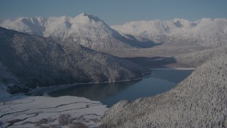 AK0001_1921 - 4K aerial stock footage descending toward Carmen Lake surrounded by snow covered mountains, Alaska
