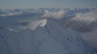 AK0001_1937 - 4K stock footage aerial video fly by snowy mountain range reveal, wooded valley, Chugach Mountains, Alaska