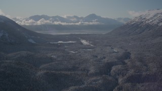 AK0001_1957 - 4K aerial stock footage fly over wooded valley between snowy Chugach Mountains, Girdwood, Alaska