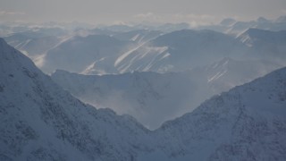 AK0001_1976 - 4K aerial stock footage snow covered windblown mountains and low clouds in Kenai Mountains, Alaska