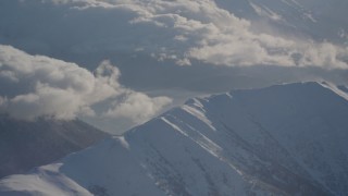 AK0001_1985 - 4K aerial stock footage cloudy Kenai Mountains, snow covered, windblown Chugach Mountains, Alaska