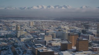 AK0001_2017 - 4K aerial stock footage snowy downtown Anchorage with cloud covered Chugach Mountains, Alaska