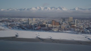 AK0001_2020 - 4K aerial stock footage snowy Downtown Anchorage, descend toward frozen shore of Cook Inlet, Alaska