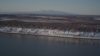AK0001_2033 - 4K aerial stock footage flying over snowy, wooded shore of Point MacKenzie, Alaska