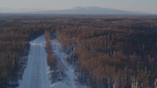 AK0001_2045 - 4K aerial stock footage following a deserted snowy rural highway in Point MacKenzie, Alaska