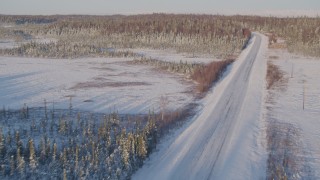 AK0001_2046 - 4K aerial stock footage following a deserted snowy rural highway in Point MacKenzie, Alaska