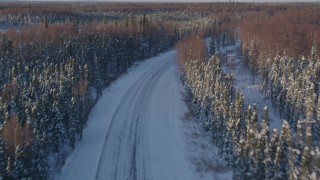 AK0001_2047 - 4K aerial stock footage following a deserted rural snow covered highway in Point MacKenzie, Alaska