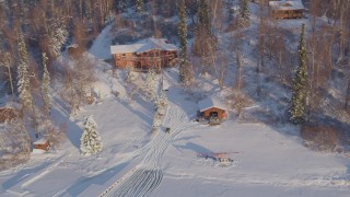 AK0001_2049 - 4K aerial stock footage a house and helicopter in a snowy forest in Big Lake Area, Alaska