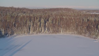 AK0001_2050 - 4K aerial stock footage flying over frozen lakes, snowy forest in Big Lake Area, Alaska