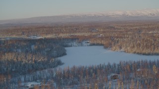 AK0001_2068 - 4K aerial stock footage houses near frozen lake, snowy forest in Knik-Fairview, Alaska, sunset