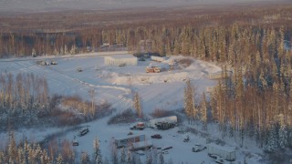 AK0001_2069 - 4K aerial stock footage approach building surrounded by snowy forest in Knik-Fairview, Alaska, sunset