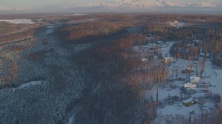 AK0001_2071 - 4K aerial stock footage approach Shawn Field, reveal snowy neighborhood in Wasilla, Alaska, sunset