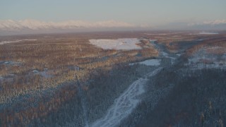AK0001_2072 - 4K aerial stock footage flying over snowy forest toward Shawn Field at sunset, Wasilla, Alaska