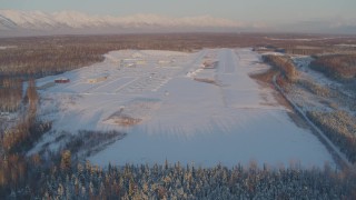 AK0001_2073 - 4K aerial stock footage descending toward snowy runway of Shawn Field at sunset, Wasilla, Alaska