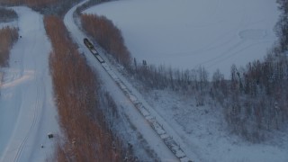 AK0001_2080 - 4K aerial stock footage a snow covered train running by Jacobsen Lake at sunset, Wasilla, Alaska
