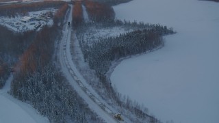 AK0001_2081 - 4K aerial stock footage a snow covered train running around Jacobsen Lake at twilight, Wasilla, Alaska