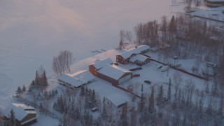 AK0001_2084 - 4K aerial stock footage orbiting a snow covered house on Lucile Lake at sunset, Wasilla, Alaska