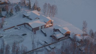 AK0001_2085 - 4K aerial stock footage orbiting a snow covered house on Lucile Lake at sunset, Wasilla, Alaska