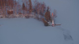 AK0001_2089 - 4K aerial stock footage snowy Cottonwood Lake, descend toward lighthouse, Wasilla, Alaska, sunset