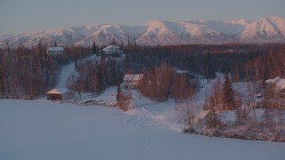 AK0001_2090 - 4K aerial stock footage fly by snow covered homes on frozen Cottonwood Lake, Wasilla, Alaska, twilight